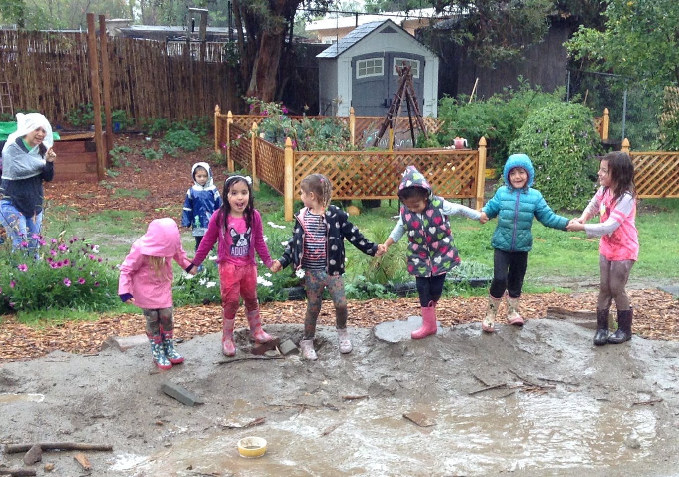 Children holding hands in a muddy outdoor area