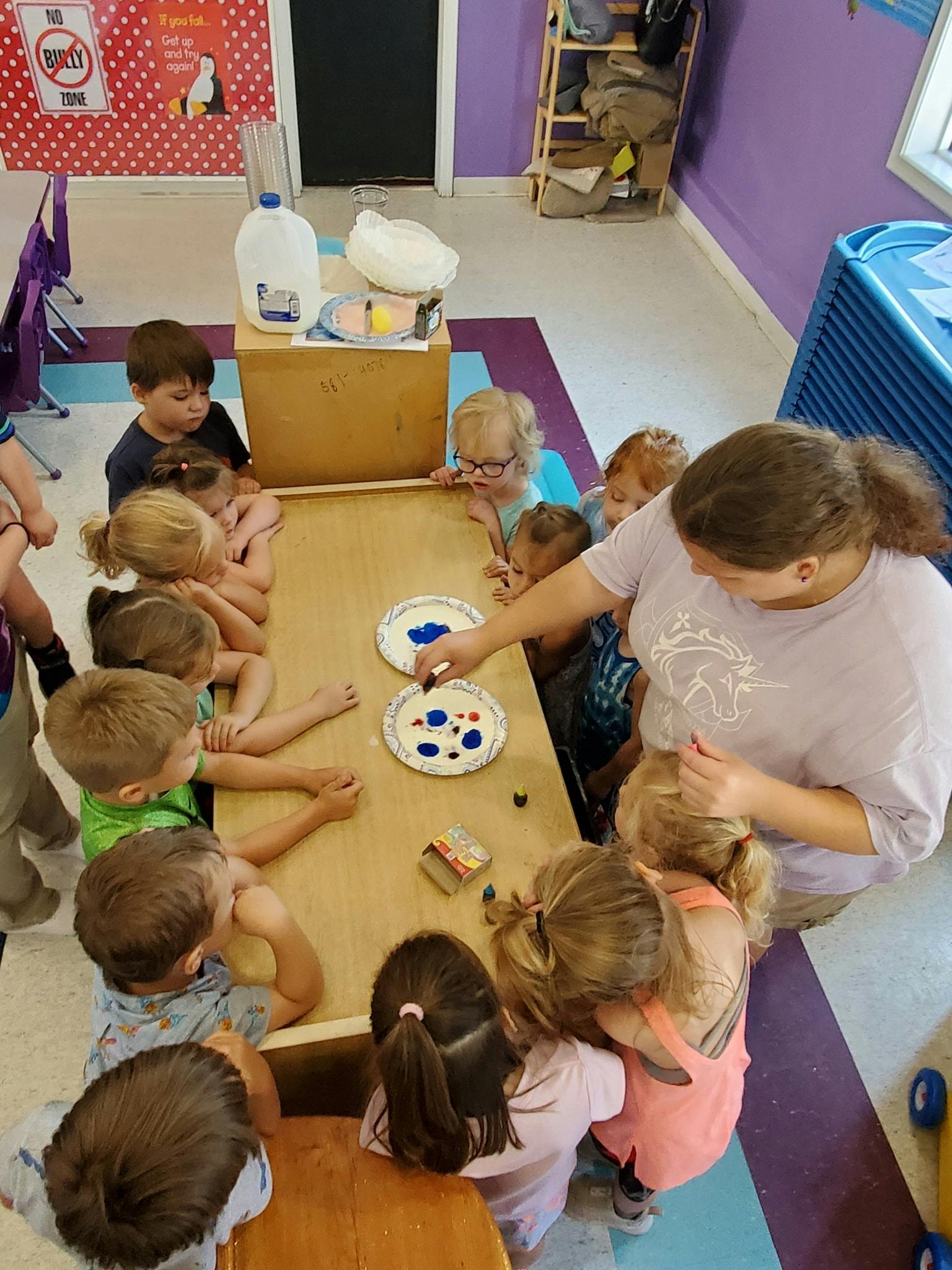Adult and children gathered around a table doing an art activity