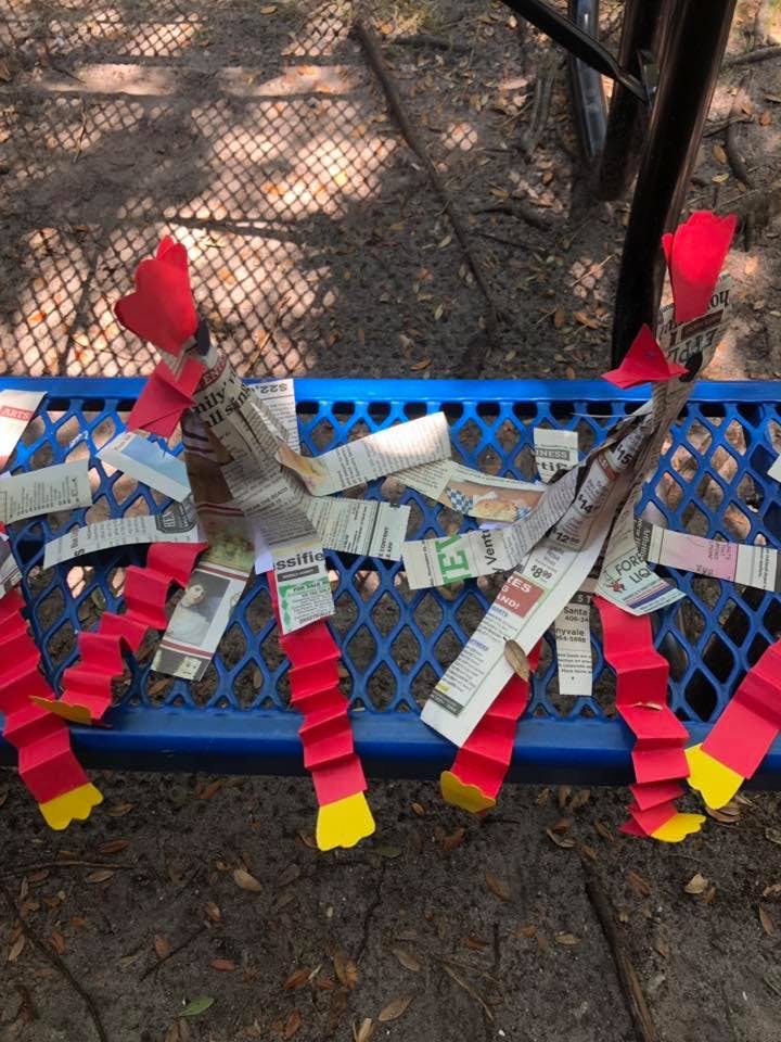 Newspaper and red paper craft figures on a blue metal bench