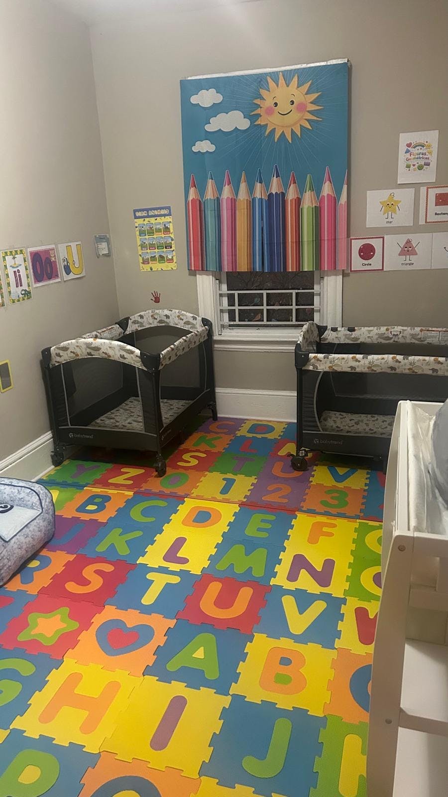 Baby room with two portable cribs and ABC floor mats