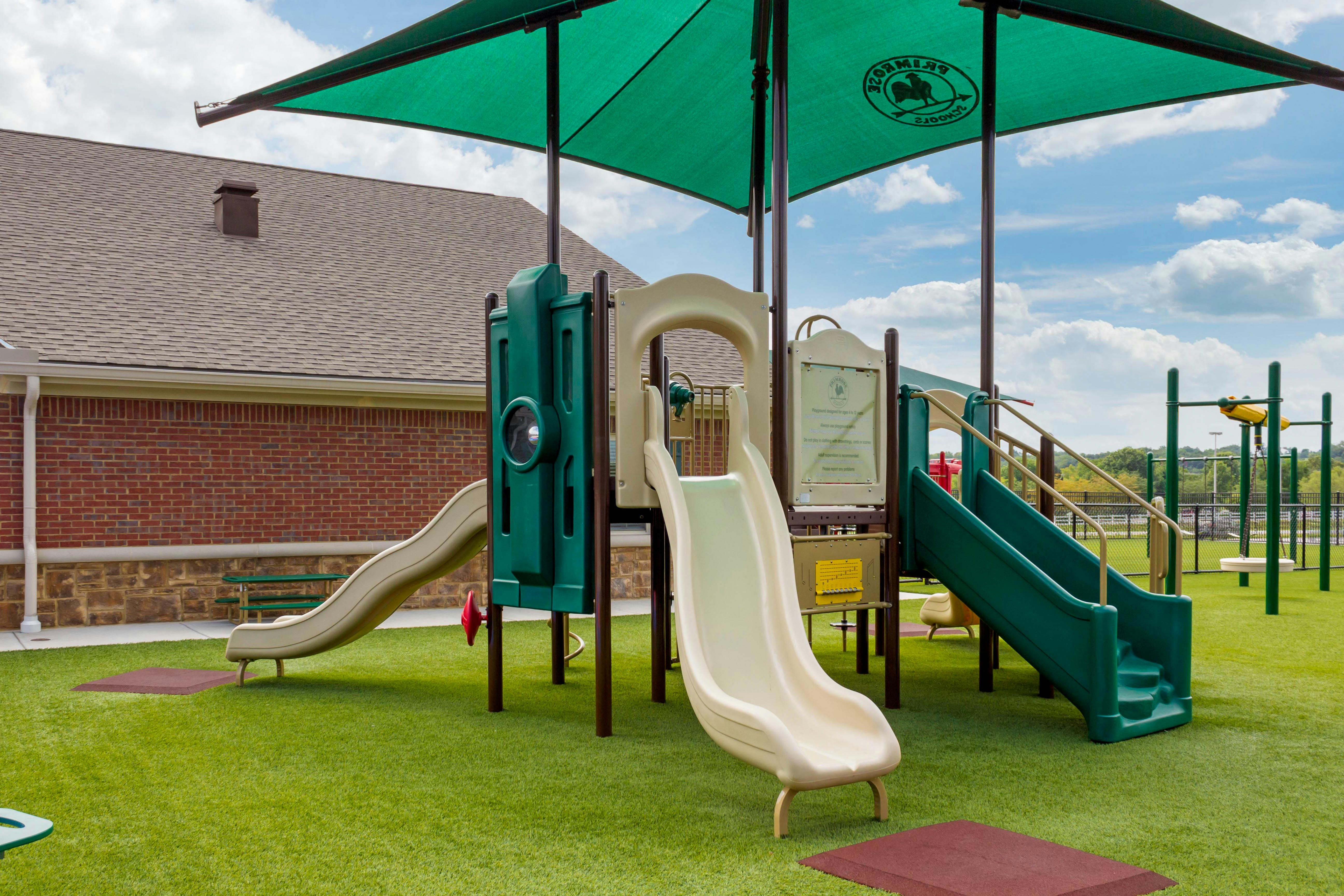 Playground with multiple slides, climbing structures, and swings under a sunshade