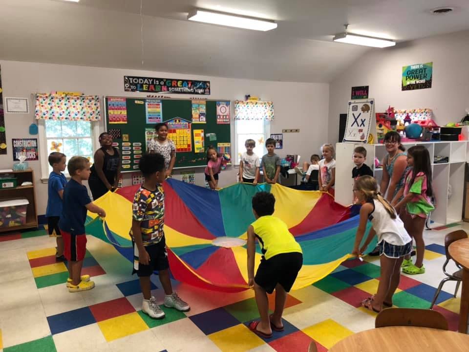 Children playing with a colorful parachute in a classroom