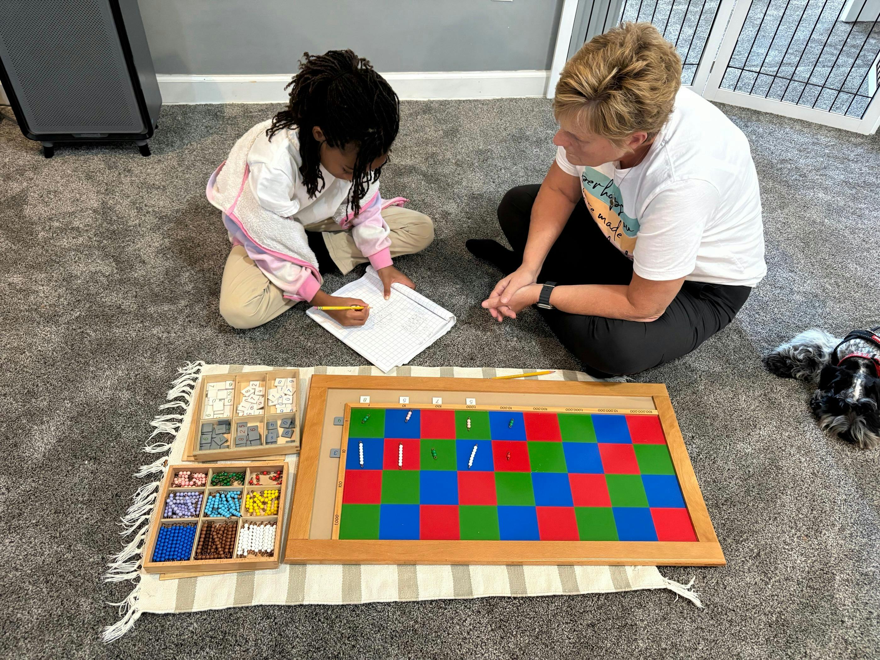 Adult and child on floor with colorful learning board and counting blocks