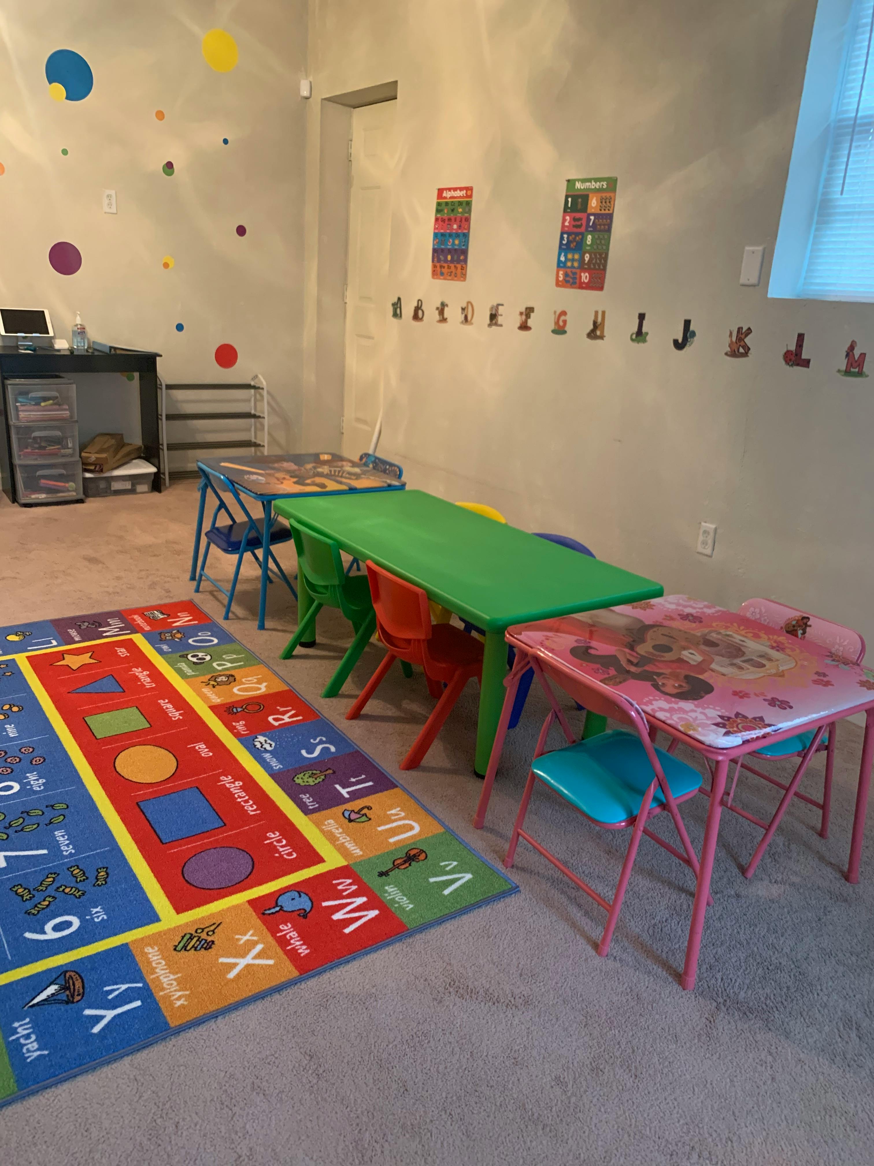 Children's play area with colorful rug, small tables, and chairs