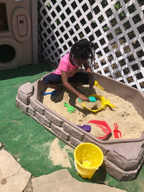 Child playing in a sandbox with sand toys