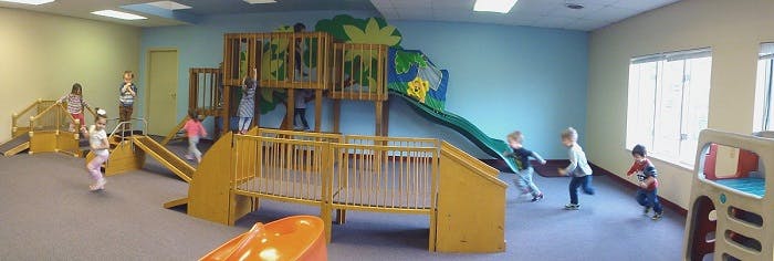 Children playing on an indoor playground structure with slides and climbing structures