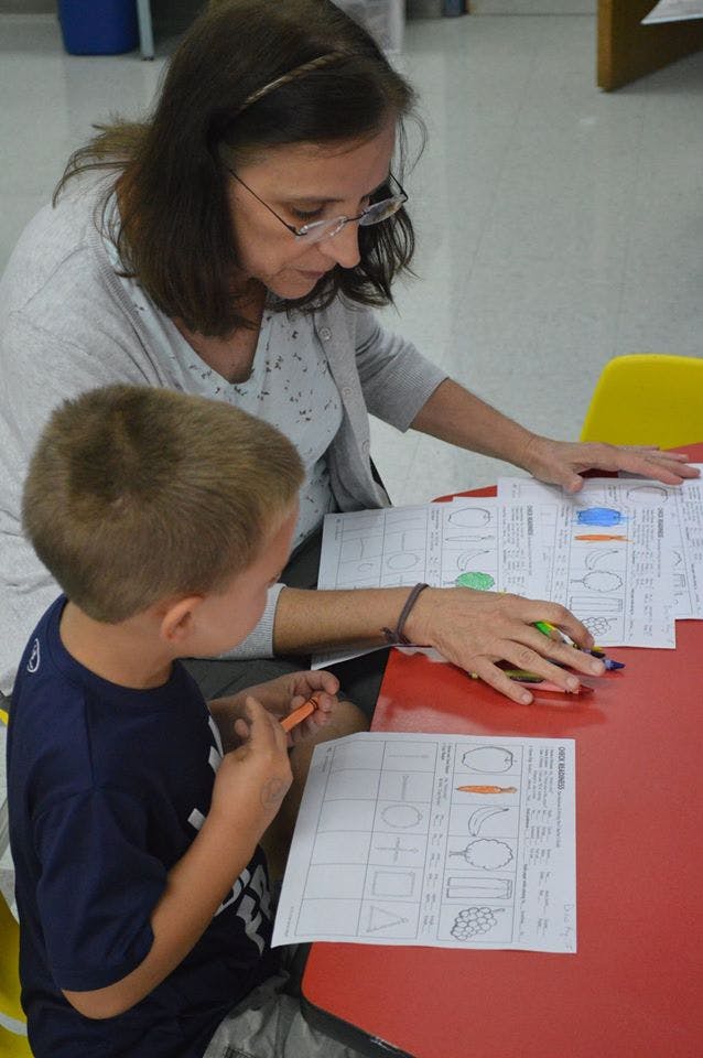 Adult and child coloring worksheets at a red table