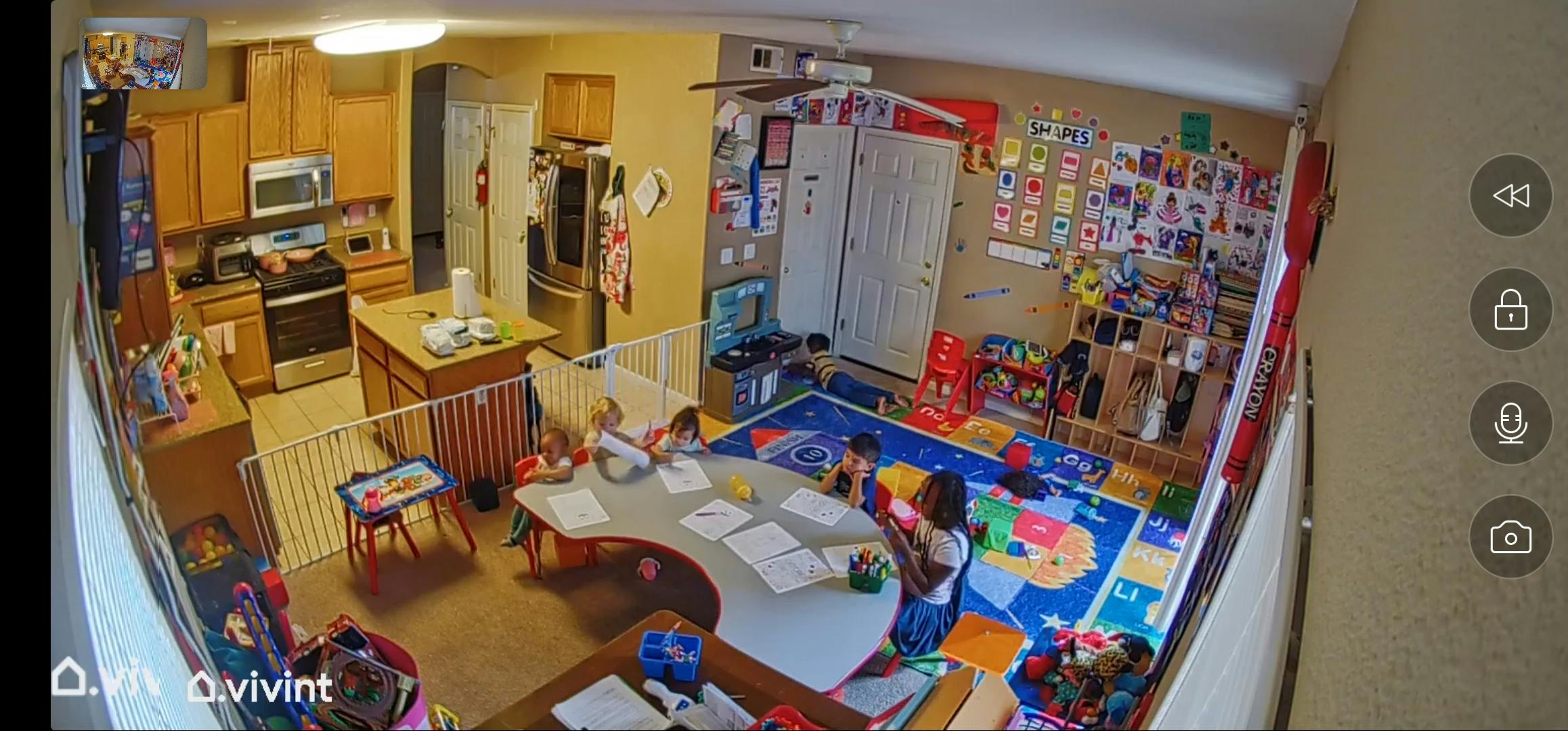 Two children playing in a room with a kitchen in the background