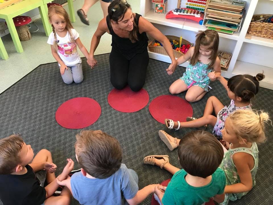 Adult and children holding hands in a circle on red mats