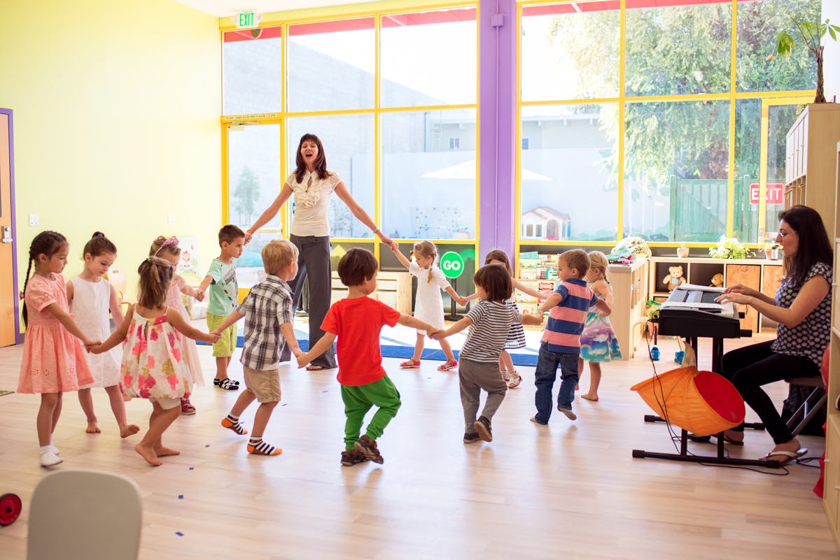 Adults and children holding hands in a circle in a classroom