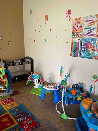 Playroom with crib, alphabet rug, and various baby toys