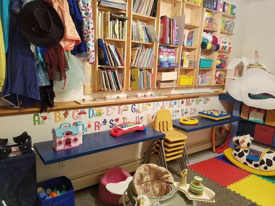 Children's play area with shelves of books, small tables, and toys
