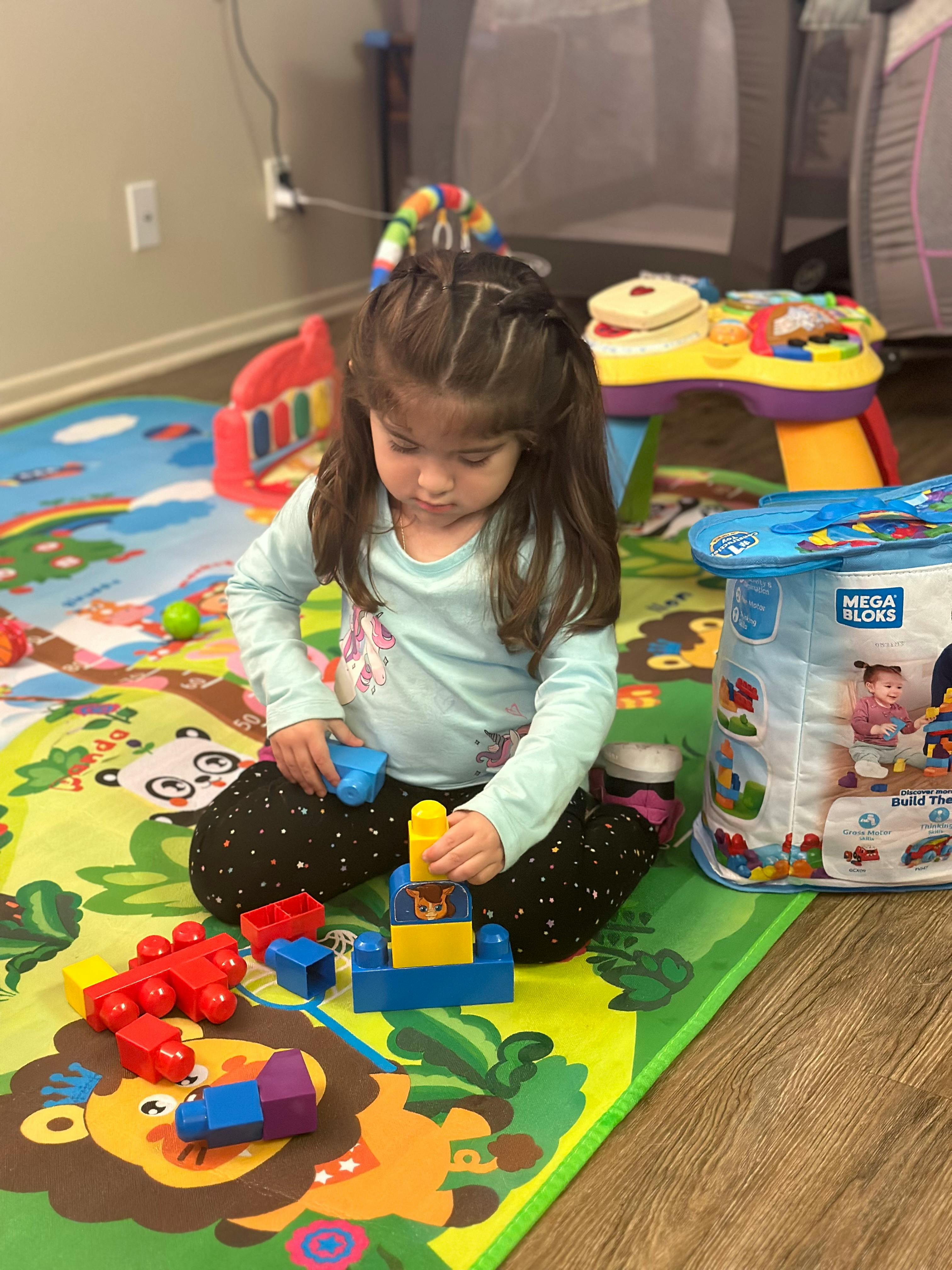 Child playing with colorful building blocks on a mat