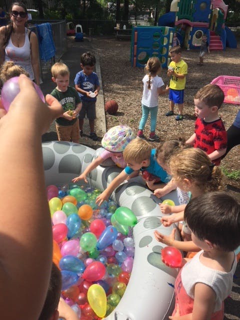 Children playing with water balloons in an inflatable pool