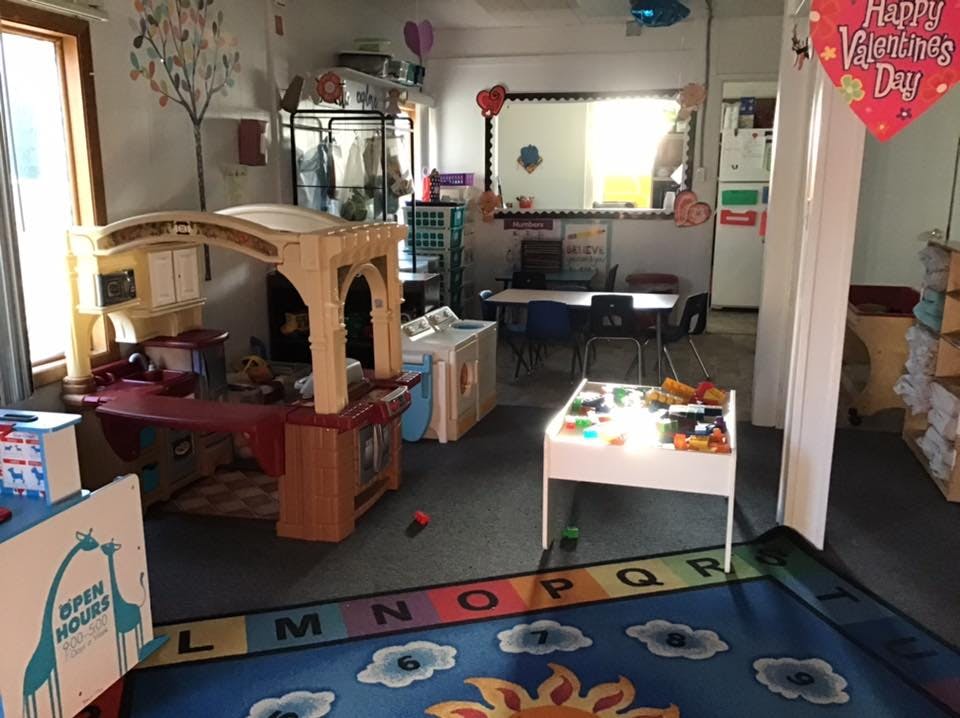 Playroom with a play kitchen, tables, and a colorful alphabet rug
