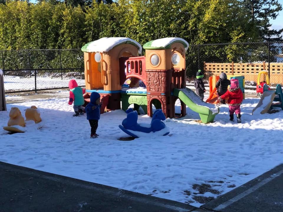 Children playing on a snow-covered playground with play structures
