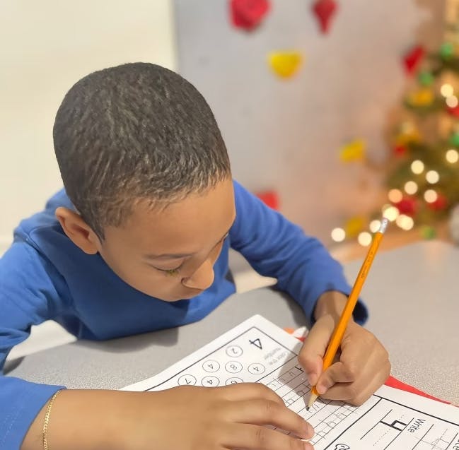Child writing on a worksheet with a pencil