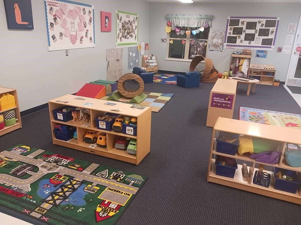Classroom with shelves of toys, play rugs, and various activity stations