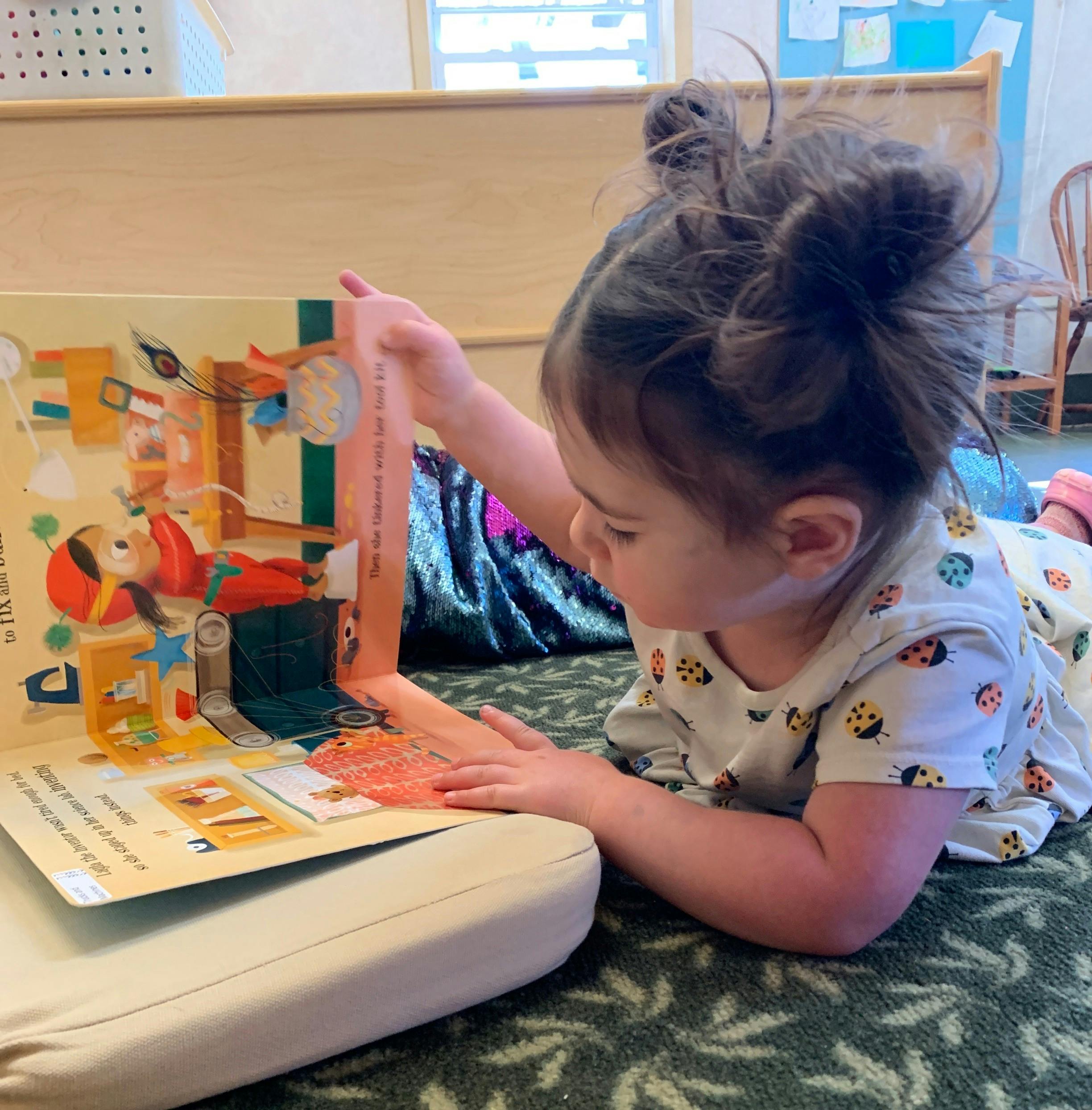 Child lying on floor reading a pop-up book