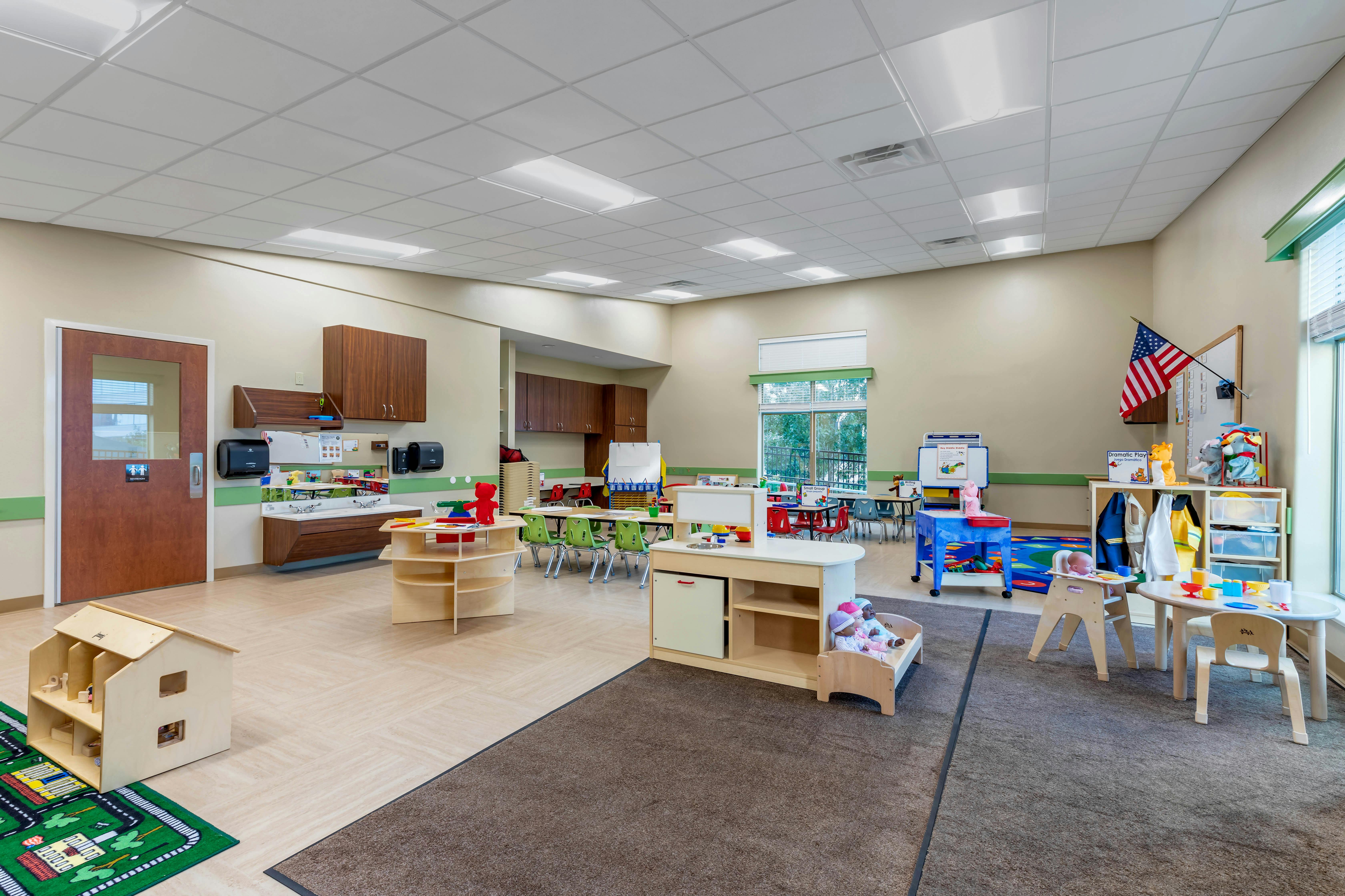 Classroom with play areas, small tables, chairs, and learning materials