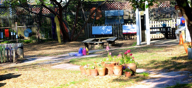 Outdoor area with potted plants in the foreground and a wooden table in the background