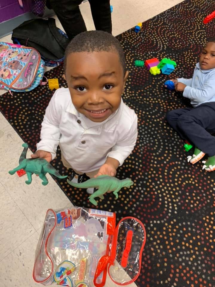 Child holding two green dinosaur toys
