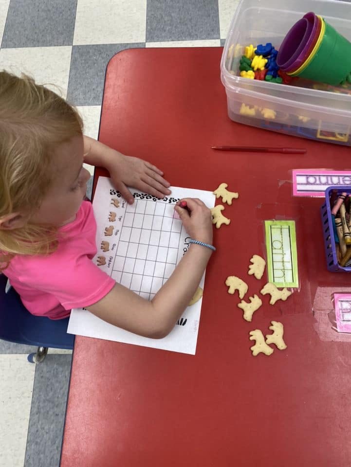 Child placing bear-shaped counters on a grid worksheet