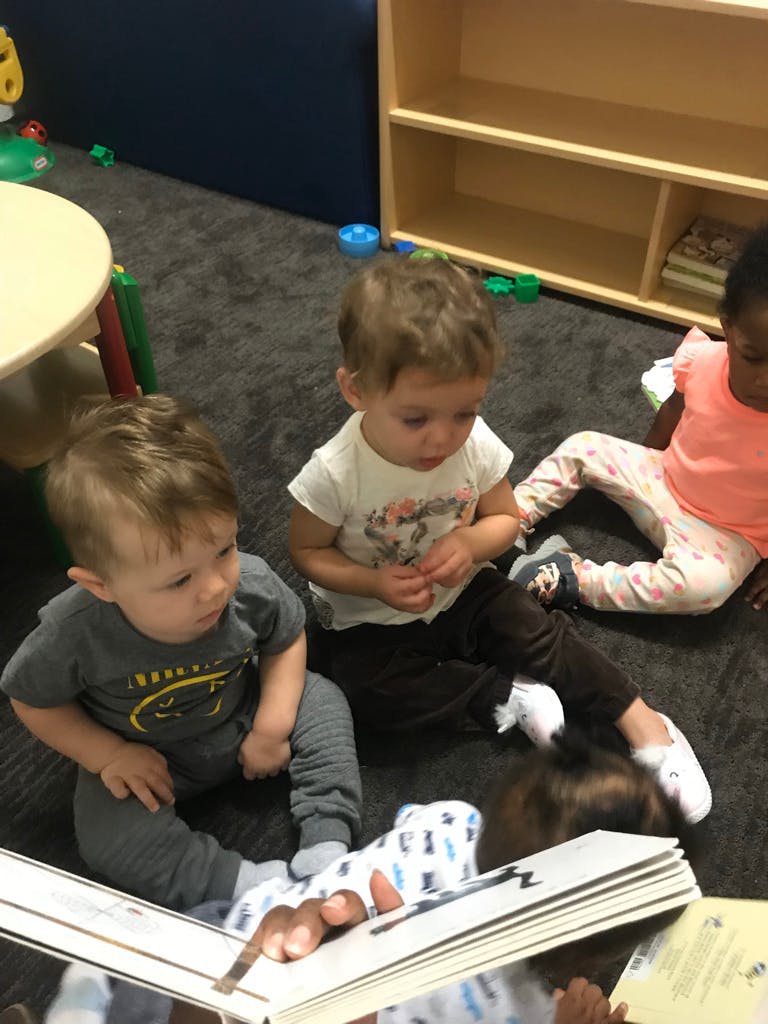 Three children sitting on the floor looking at a book
