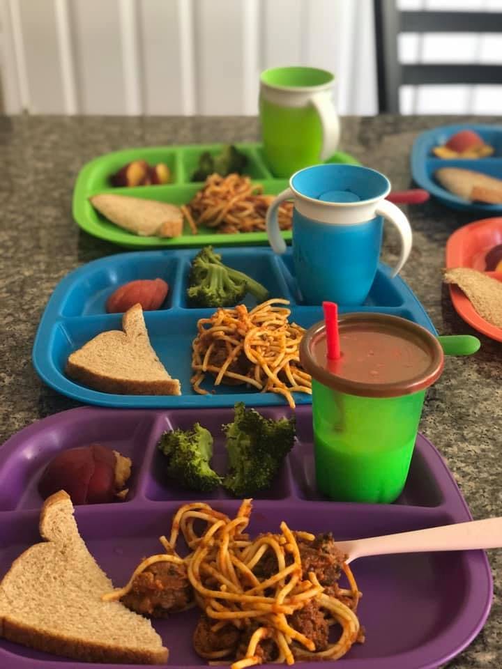 Multiple plates of spaghetti, broccoli, and bread