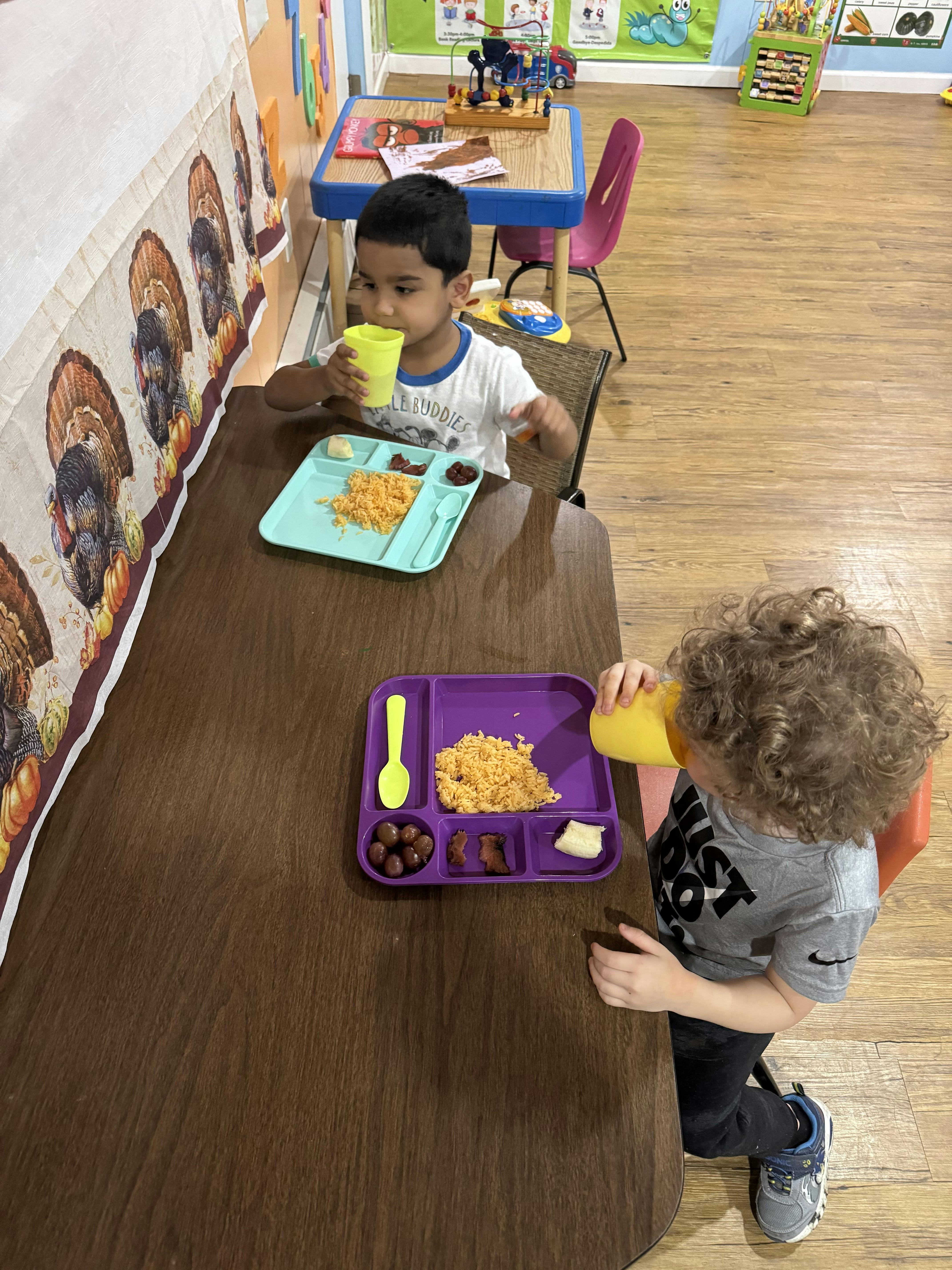 Two children eating at a table in a classroom
