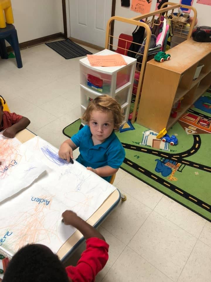 Child drawing at a table in a classroom