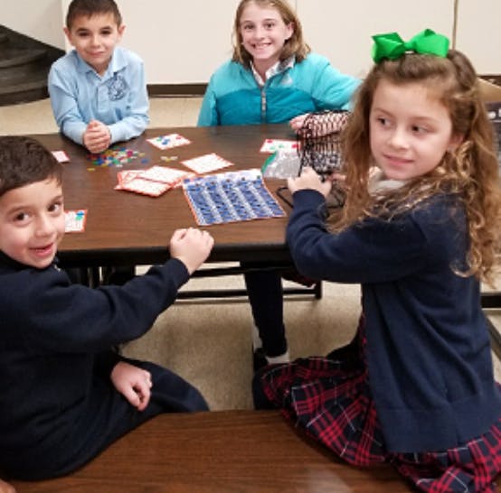 Four children sitting at a table with game pieces