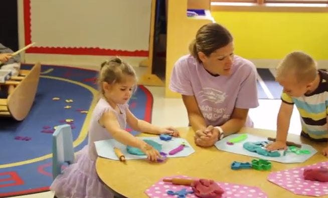 Adult and two children playing with modeling clay at a table