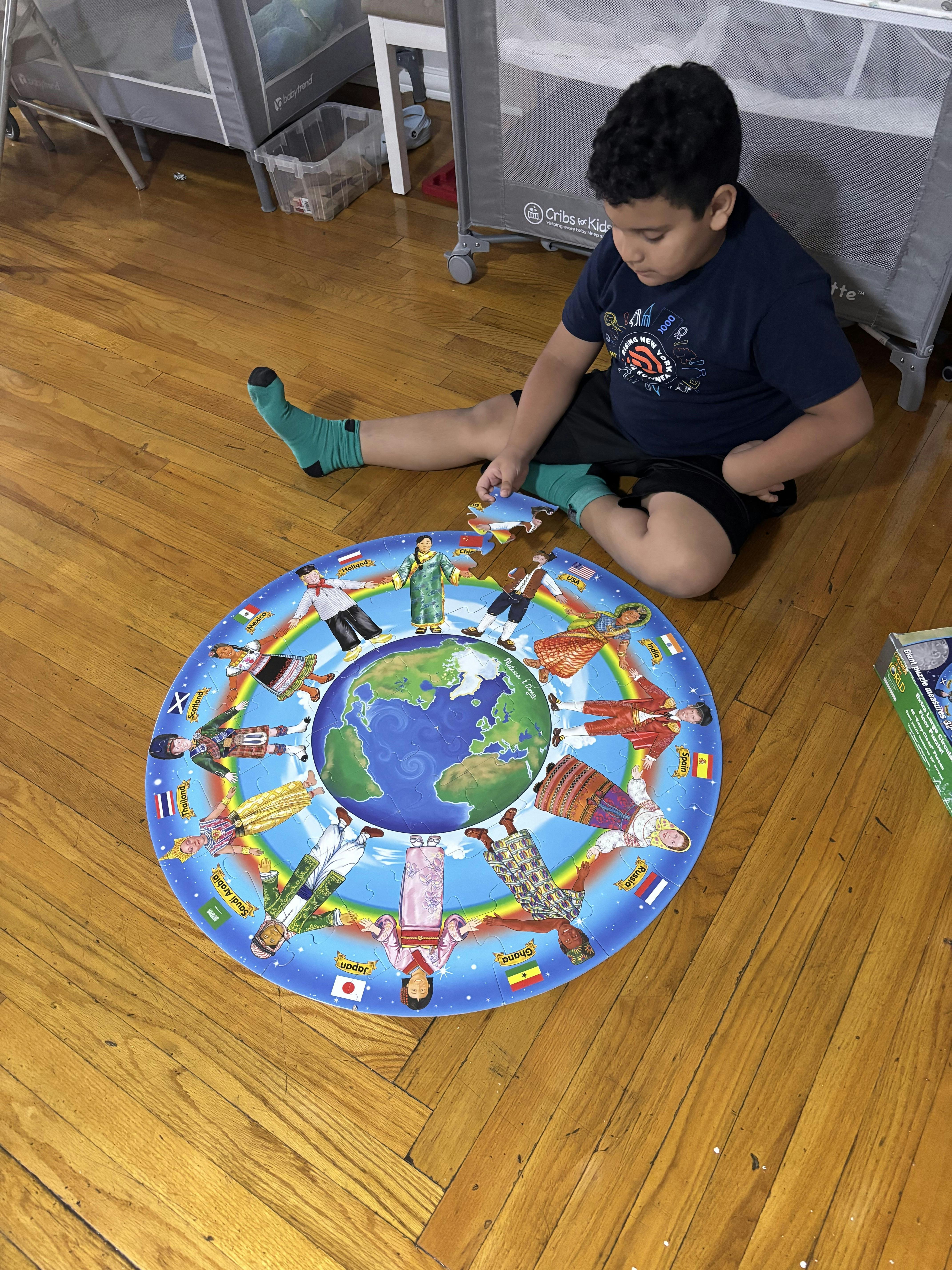 Child sitting on a wooden floor completing a circular world puzzle