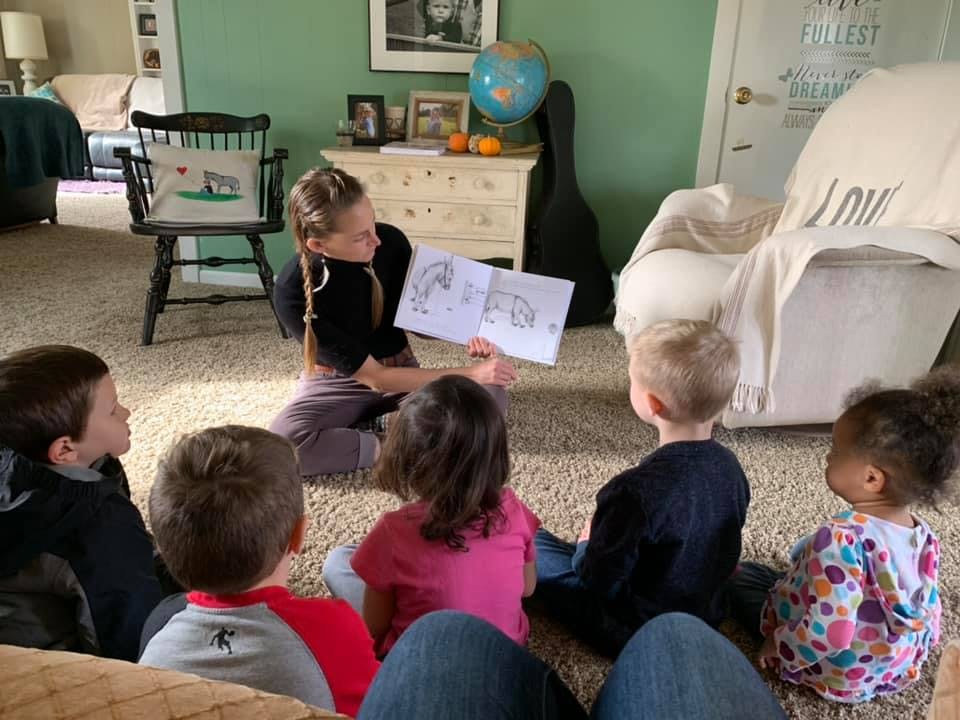 Person reading a book to children sitting on the floor