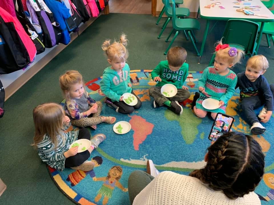Adult reading to children sitting on a world map rug