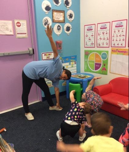 Adult and children doing yoga poses in a classroom
