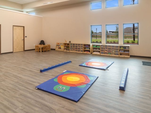 Large empty classroom with play mats and shelves of toys