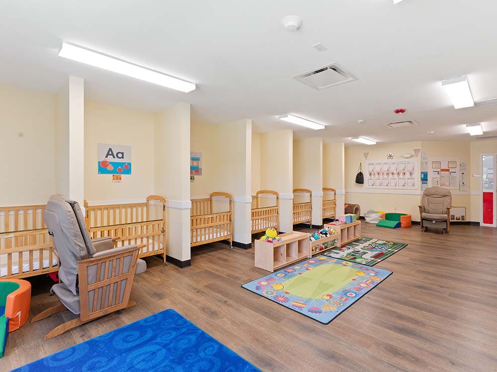 Cribs, rocking chairs, and colorful rugs in a nursery room