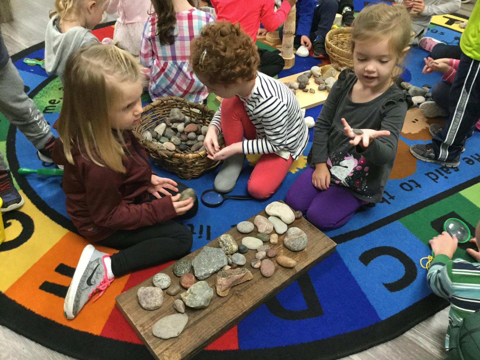 Children on a rug examining rocks