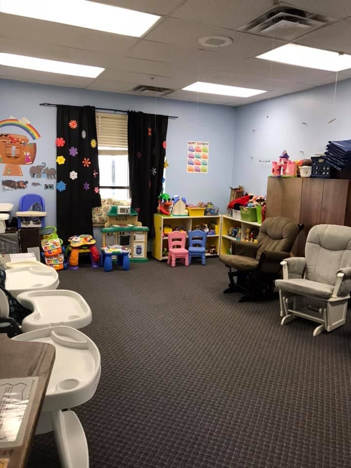 Playroom with high chairs, small tables, chairs, and shelves of toys