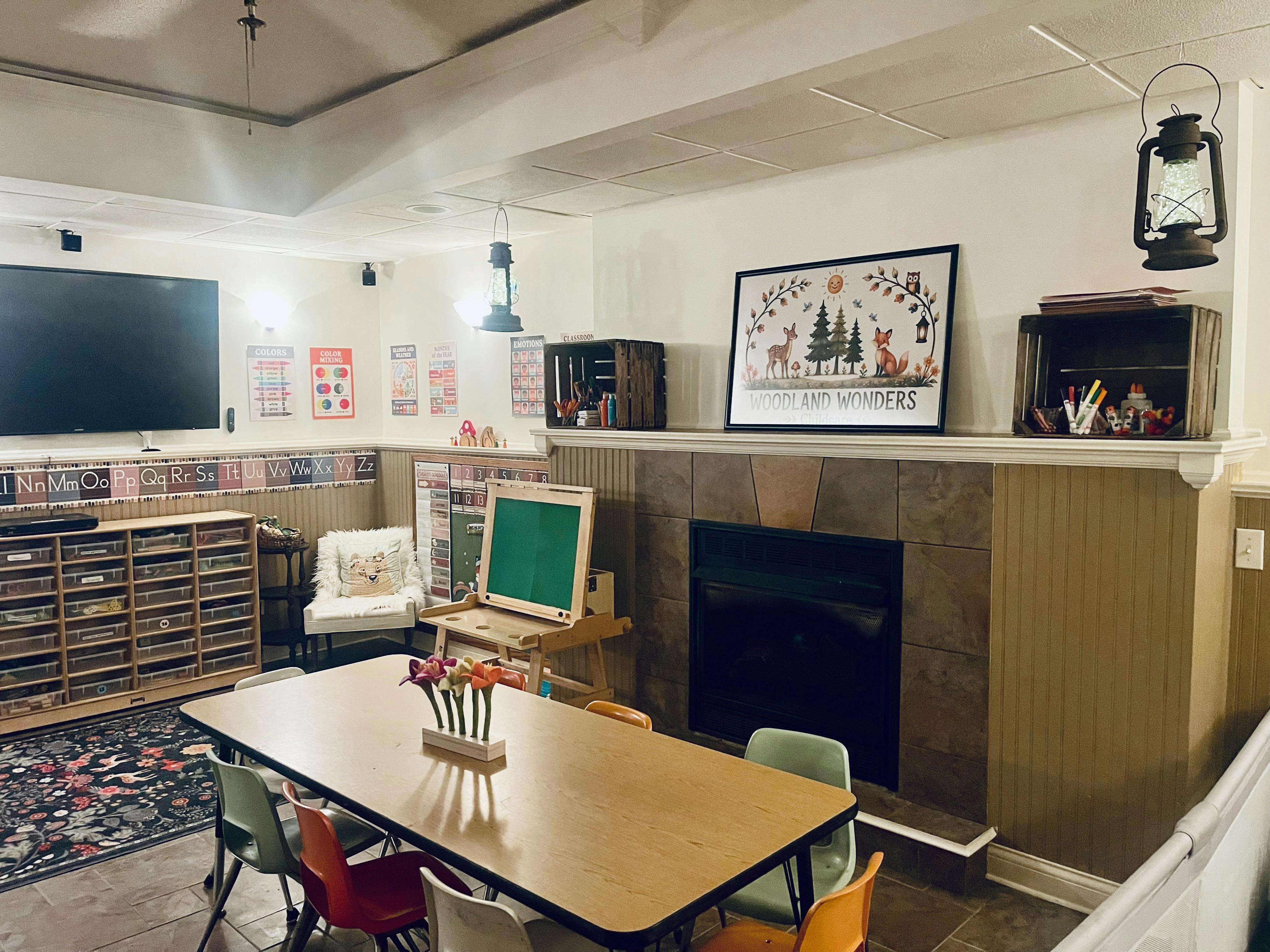 Classroom with child-sized chairs around a table, fireplace, and educational art