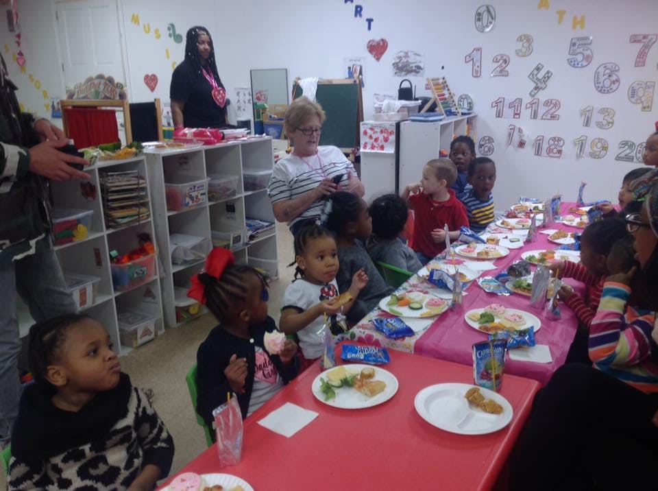 Adults and children seated at a long table with plates of food