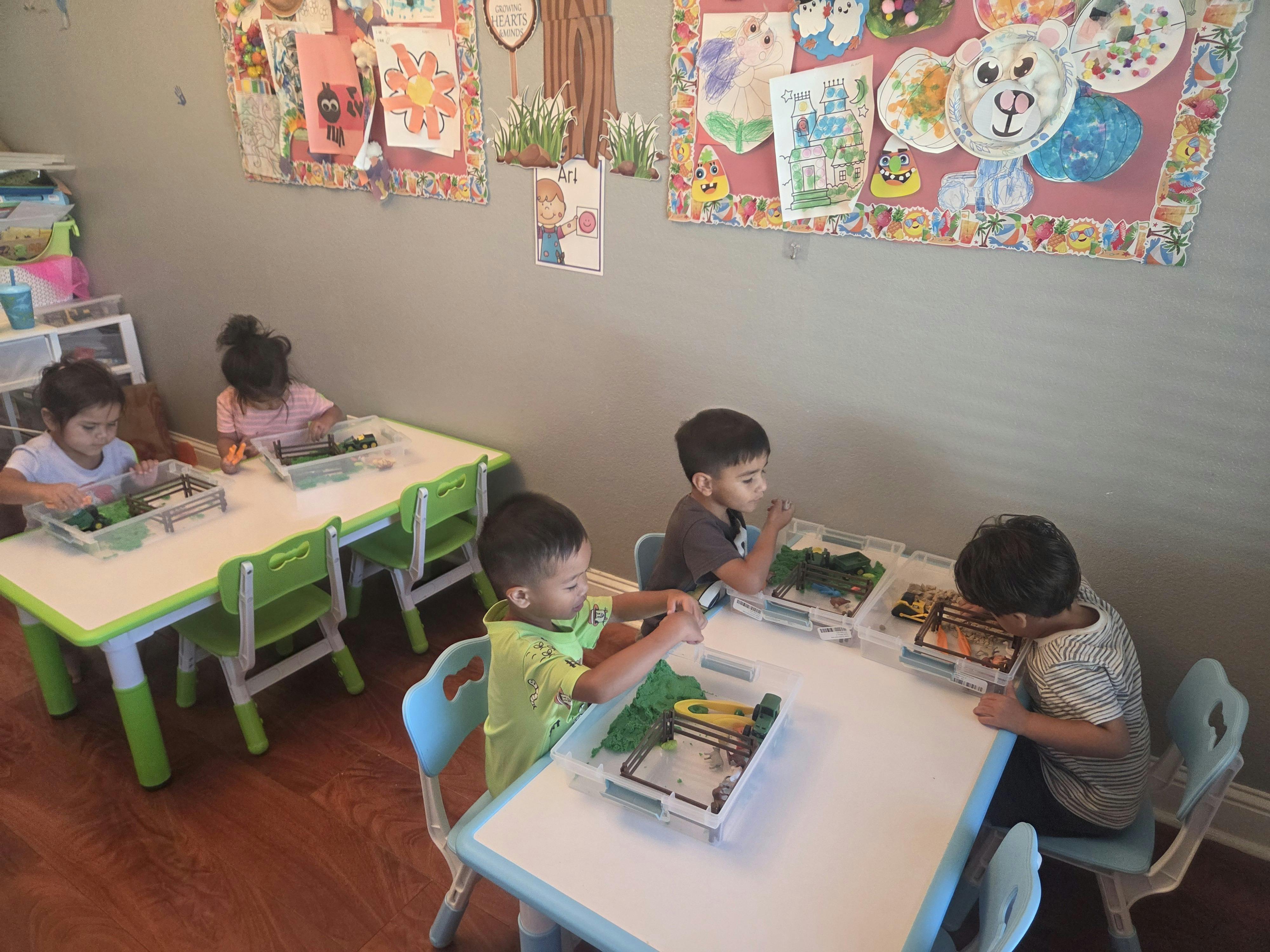 Children sitting at tables playing with sensory bins in a classroom