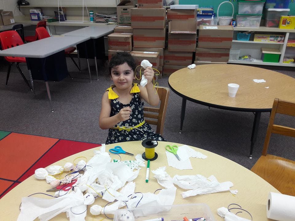Child holding a craft item in a classroom