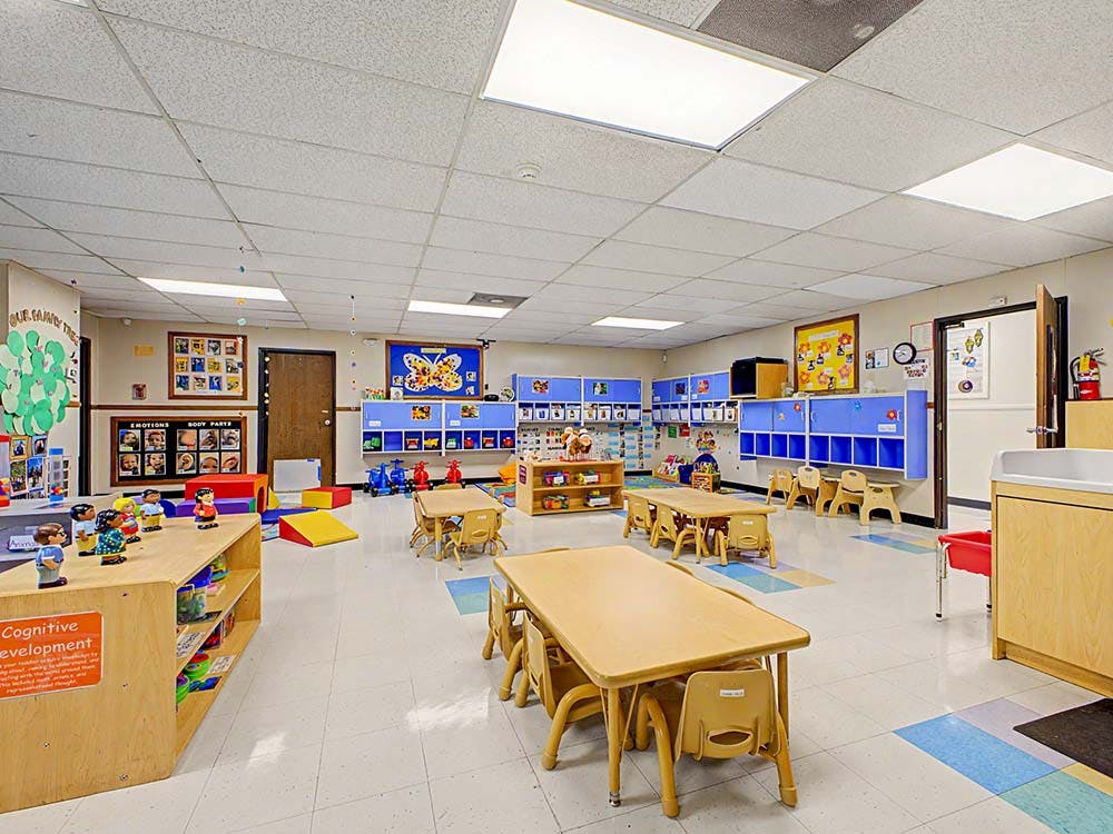 Empty preschool classroom with small tables and chairs