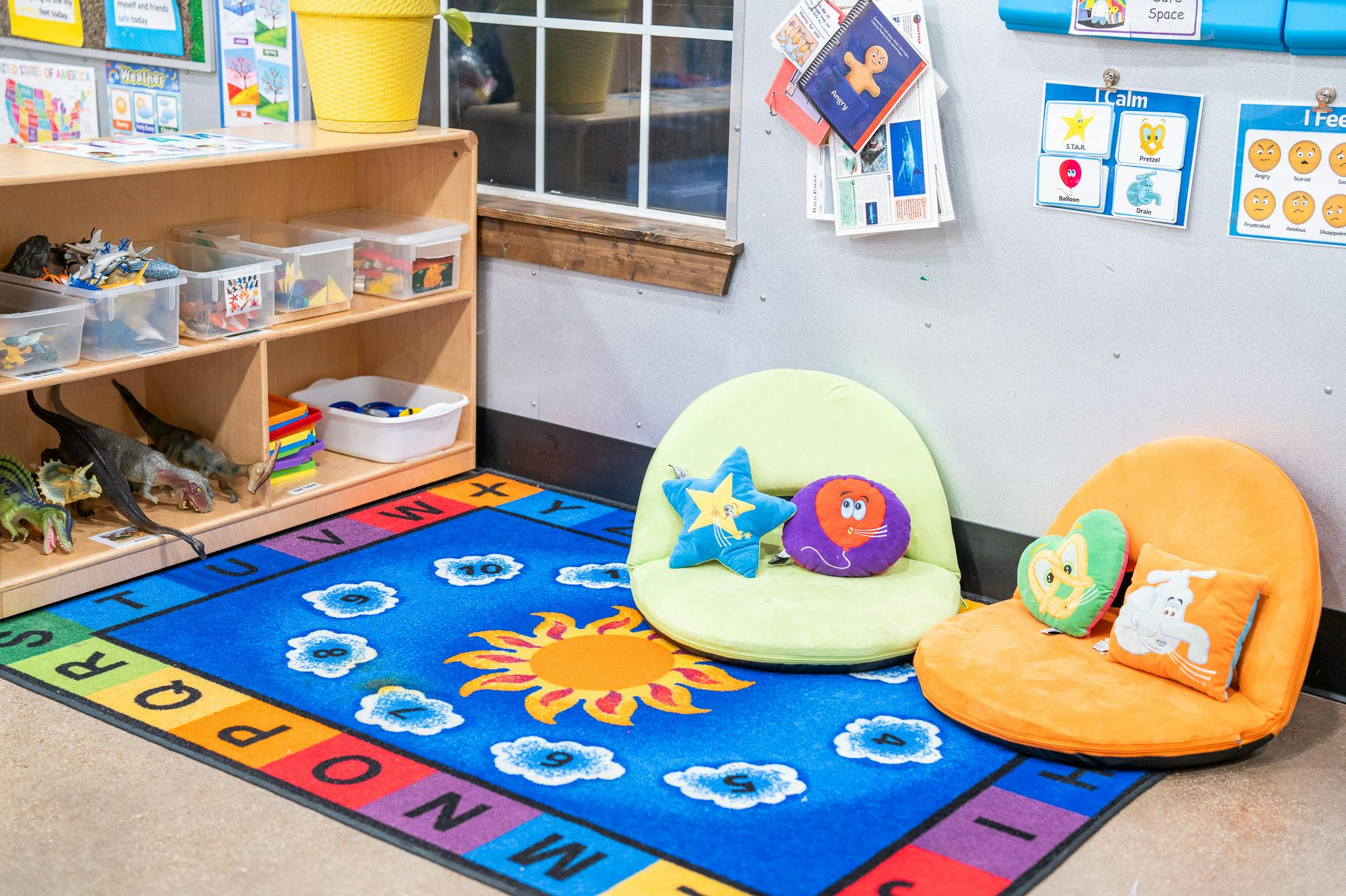Classroom corner with a colorful alphabet rug, floor seating, and toy shelves