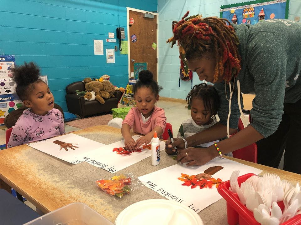 Adult helping children with crafts at a table