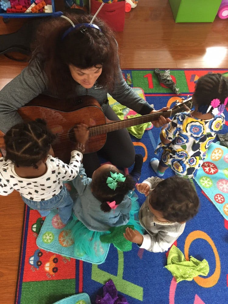 Person playing guitar for children in a classroom