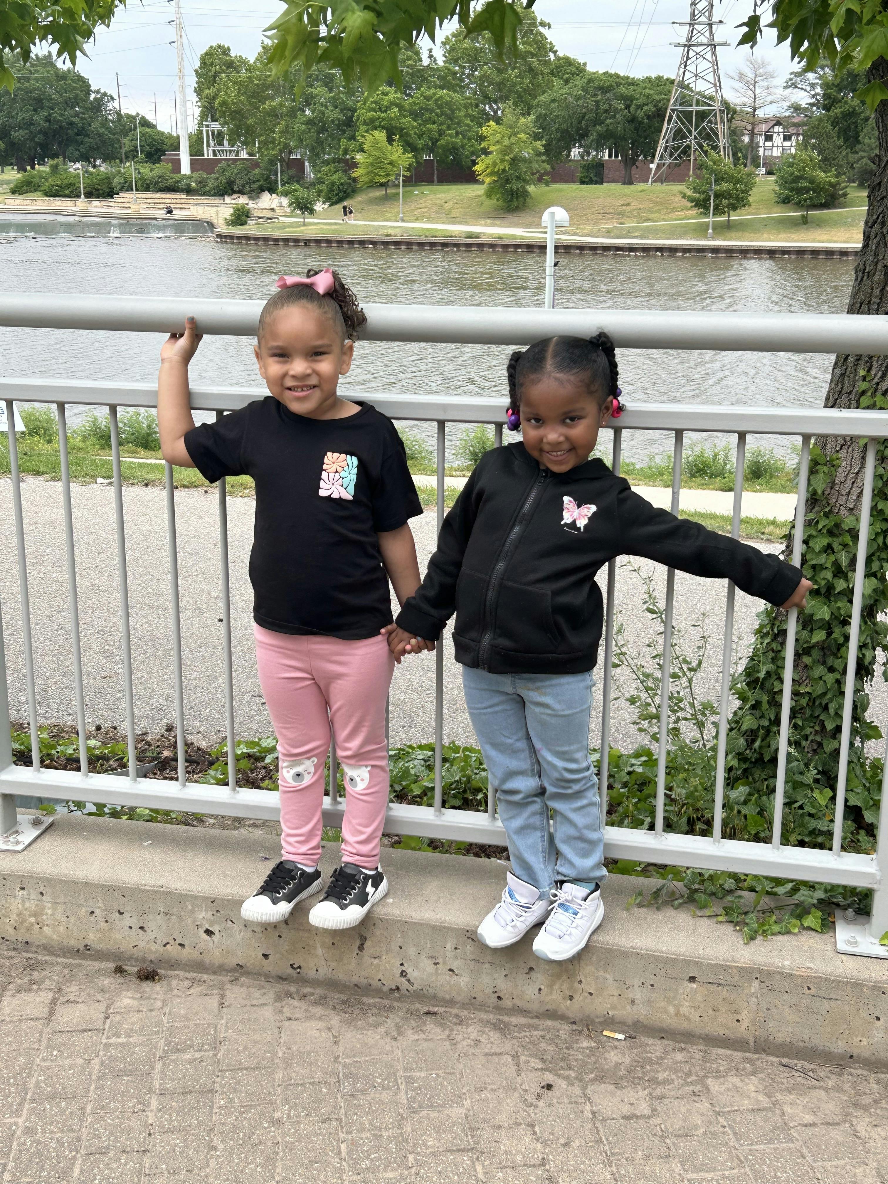 Two children standing by a fence next to a body of water
